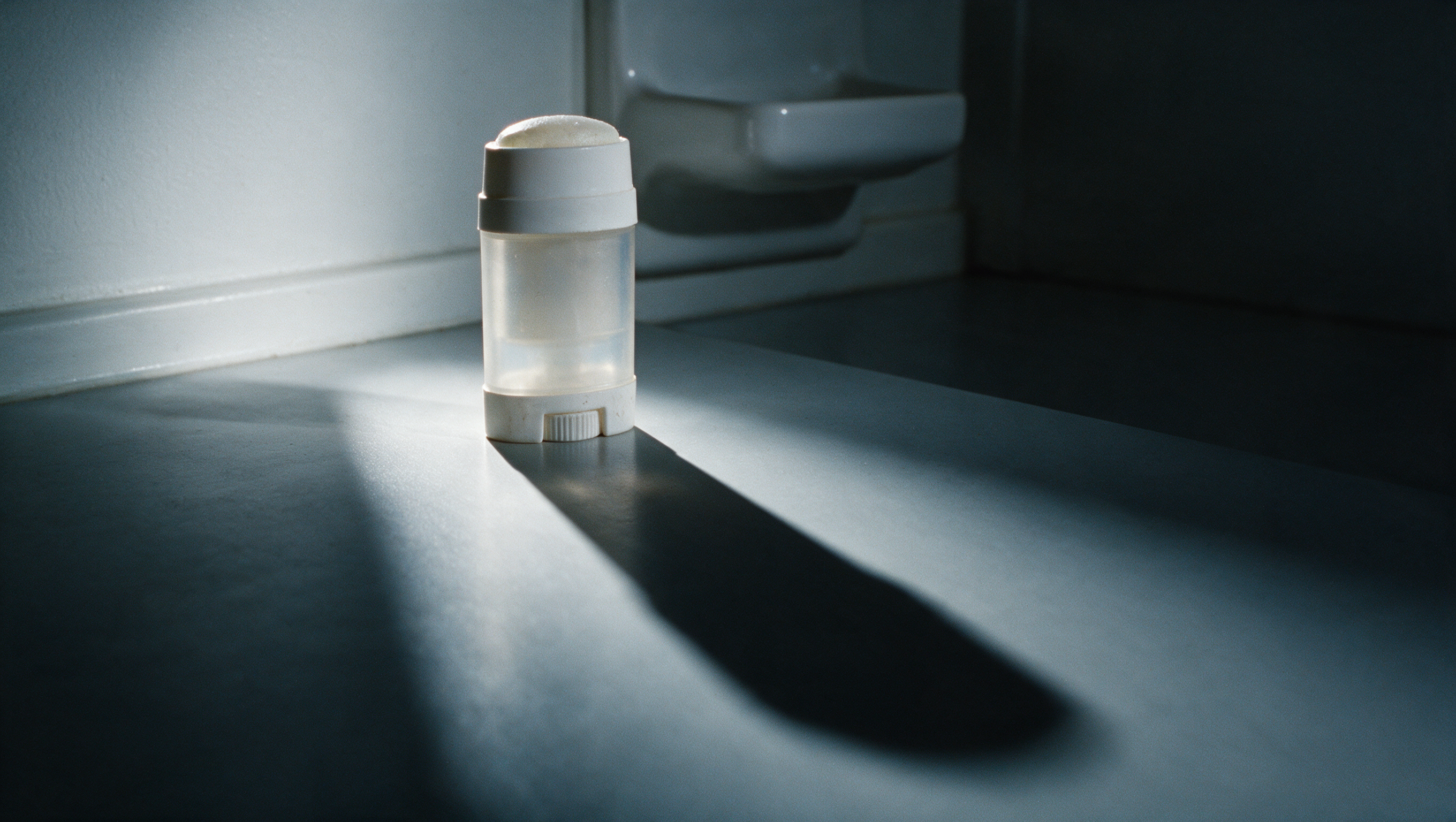 A small deodorant stick casting an enormous shadow across the counter